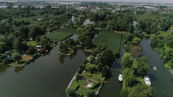 Aerial Slomo of Dutch Countryside surrounded with Small Rivers, Green Trees and Bushes, revealing Sm