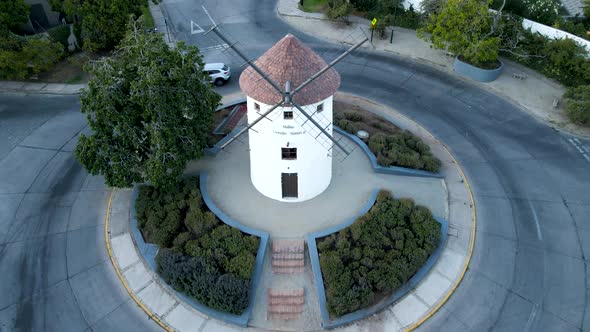 Aerial dolly out of Leonidas Montes windmill tower in roundabout with vehicles driving surrounded by