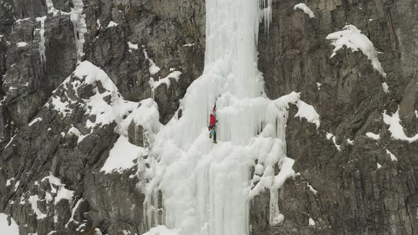 Wide aerial extreme climber taking rest on frozen cascade Mount Kineo