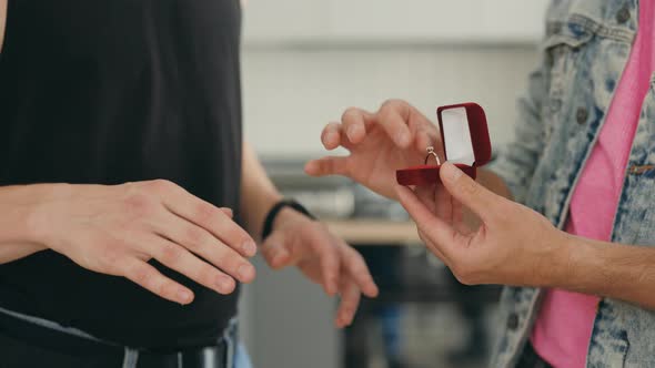 Close Up View of the Male Gays Hands Doing the Proposal Holding the Red Ring Box Standing in Their