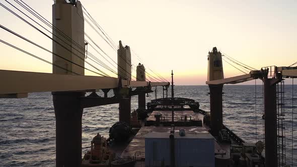 Slowmotion View of Bulk Carrier Deck Sailing Into Sunset During Ocean Transportation