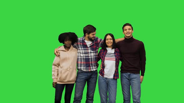 Four Happy Friends Posing for a Picture Hugging All Together and Smiling at the Camera on a Green