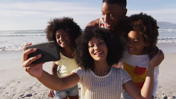 African american parents and their children taking a selfie with smartphone on the beach