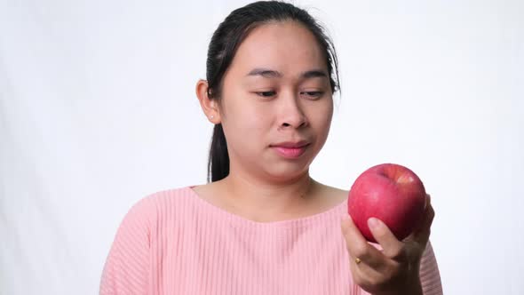 Asian woman holding an apple with a bite and smile showing strong teeth