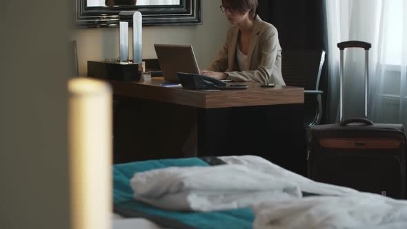 Woman Working on Laptop in Hotel Room