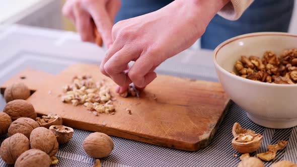 Chopping Walnuts Cores with Kitchen Knife on a Wood Cutting Board