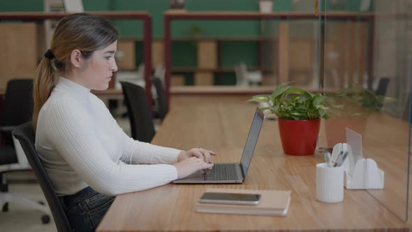 Portrait of Pensive Woman Entrepreneur Using a Laptop While Working in an Open Office Copy Space