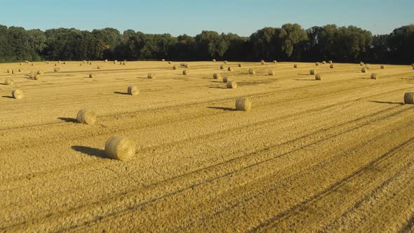 flying forward over a wheat field after harvest with bales of hay