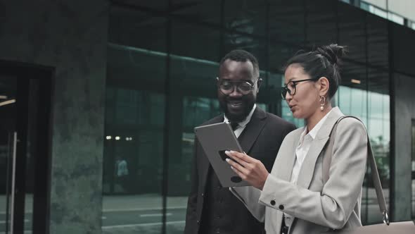 Businesspeople with Tablet Walking and Discussing Work