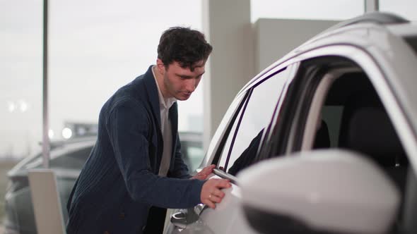 Auto Shop Charming Owner Looking at a New Car with Pleasure in a Vehicle Dealership