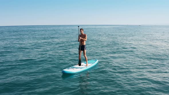 Man Paddles On The Board In The Ocean