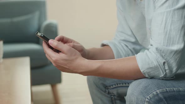 Male Hands Using Smartphone In Living Room
