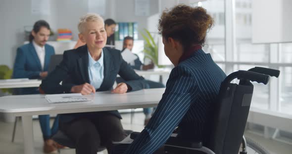 Caucasian Businesswoman in Wheelchair Consulting Colleague in Office