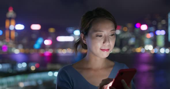 Woman use of smart phone in city at night