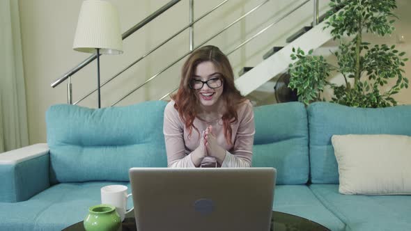 Smiling Beautiful Girl With Glasses Works At The Computer And Enjoys The Good News