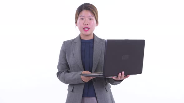 Happy Young Asian Businesswoman Talking While Using Laptop