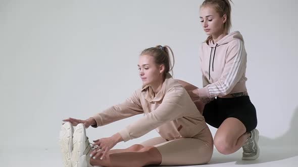 fitness instructor helps girl stretch her body muscles before training