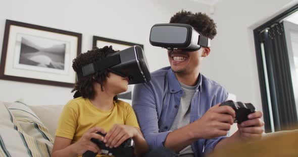 Happy biracial man and his son playing video games wearing vr headset