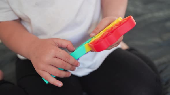 Toddler Girl with Popit Toy in Rainbow Colours