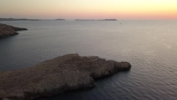 Smooth traveling of the small peninsula of Punta Galera in Ibiza. The shot reveals us the sunset at