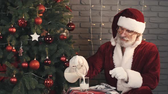 Man in Santa Costume Pouring Milk Into Empty Glass