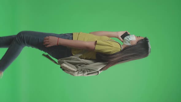 Girl Student Wearing A Mask And Talking On Mobile Phone While Walking On Green Screen