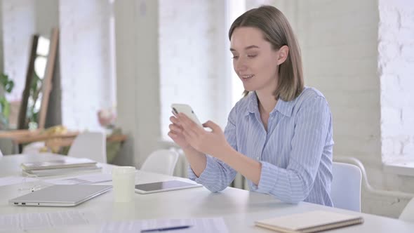 Attractive Young Woman Using Smart Phone in Office