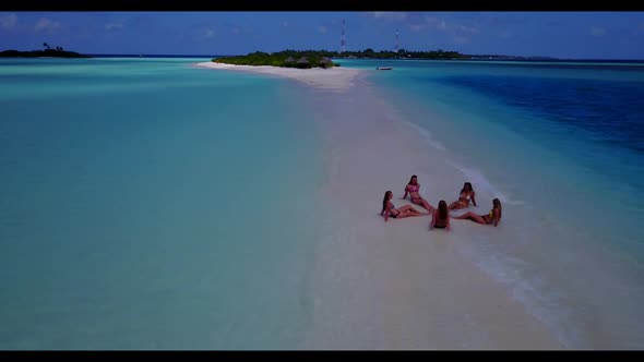 Women posing on tranquil lagoon beach holiday by blue water with white sand background of the Maldiv