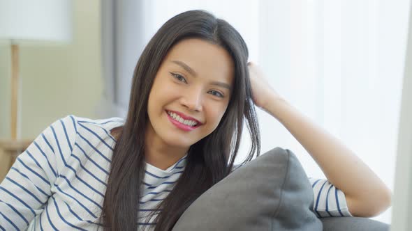 Portrait of Asian beautiful woman sit on sofa in living room at home.