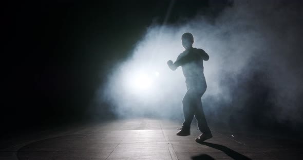 Teenage dancer performing hip hop dance in slow motion with strobe light and smoke background