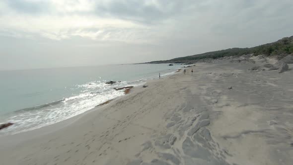 Friends walking on sandy beach near sea and enjoying sunset.