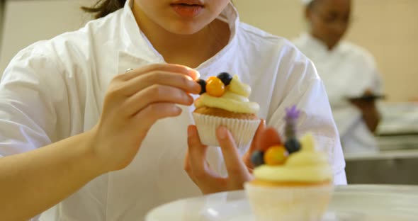 Female chef garnishing muffins in kitchen 4k