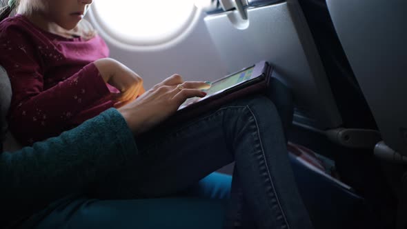 Little Girl with Mom Using Tablet PC in Airplane