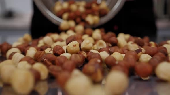 Close-up of a Pastry Chef Pouring a Lot of Hazelnuts on a Table. Slow Motion.