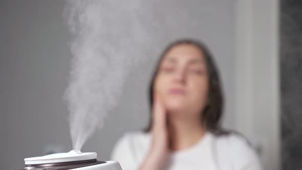 Woman Applies Moisturizing Cream on Face Near Humidifier