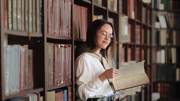 Smiling Girl in Library Near Bookshelf