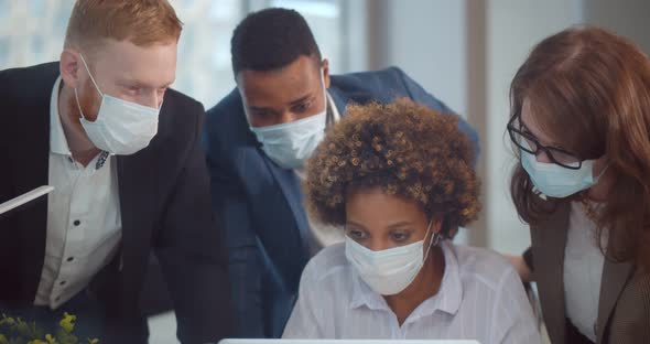 Startup Team in Safety Mask on Meeting in Modern Office Interior Brainstorming Working on Laptop