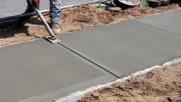 Workmen Finish and Smooth Concrete Surface on New Cement Sidewal