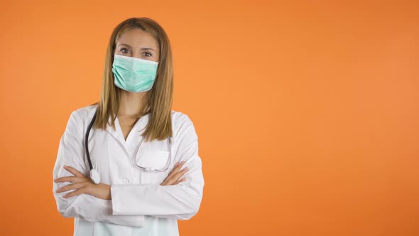 Portrait of Young Female Doctor with Medical Face Mask Holding Crossed Arms on Chest Isolated on