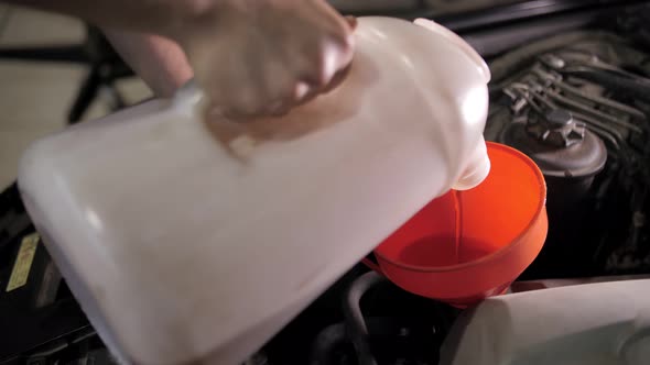 auto mechanic pours oil into the engine