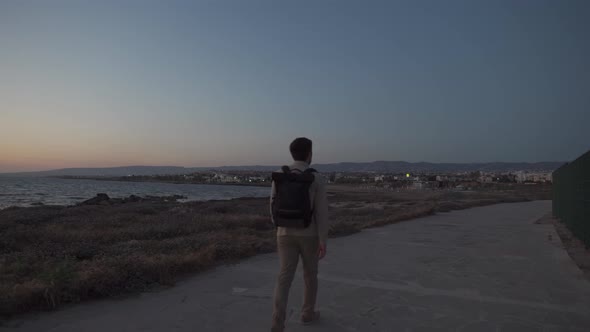 Man Tourist with Backpack Walk Along Walking Path at Rocky Coast of Mediterranean Sea in City Paphos