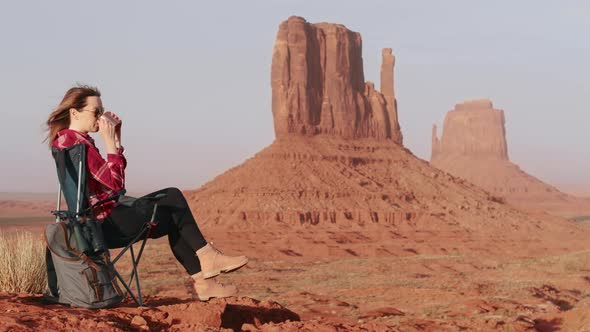 Happy Woman in Camping Chair in Desert Wilderness Red Mounting Cliff Background