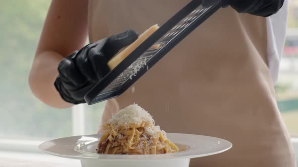 Unrecognizable Lady Cook Grating Cheese On Pasta Dish In Kitchen