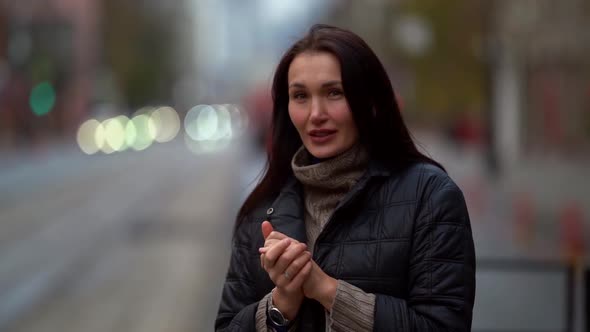 Portrait of a Woman with Long Hair in a Knitted Sweater and a Dark Coat on a Cloudy Day