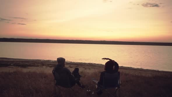 Boy and Girl Sitting in Folding Chairs Near Water Having a Conversation Talking