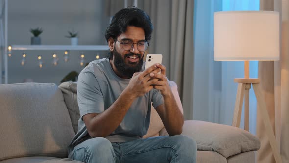 Smiling Arabian Indian Man Bearded Male Looking in Smartphone Smile Texting with Friend Girlfriend
