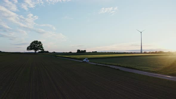 The Light of the Rising Sun Illuminates the Meadow on Which is Wind Generator