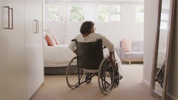 Senior mixed race woman sitting on a wheelchair. Social distancing and self isolation in quarantine