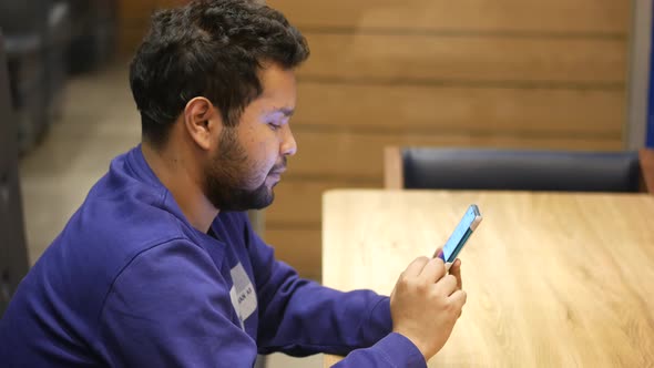 Young Man Hand Using Smart Phone Sitting on a Cafe Table