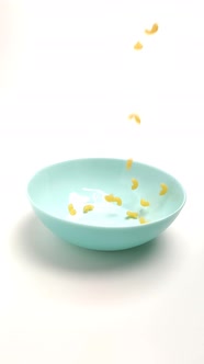 Wheat Pasta Falls on a Blue Plate on a White Background. Close-up, Slow-motion